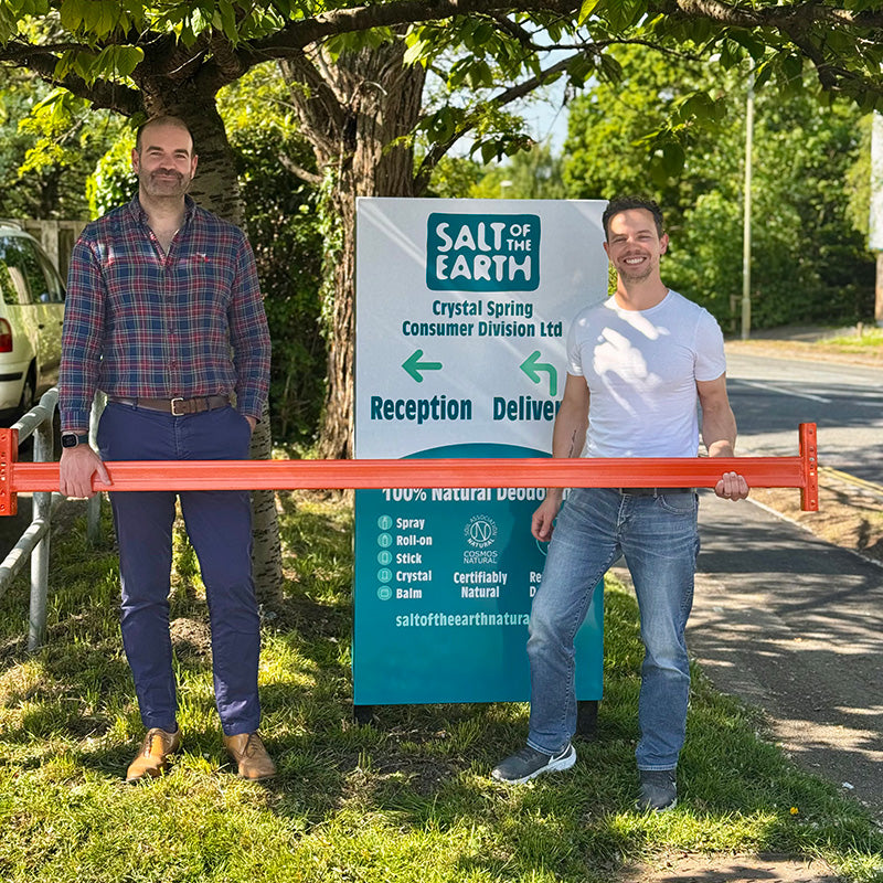 Thomas from Salt of the Earth and Brett Sanders from The Natural Deodorant Co. standing together outside the Salt of the Earth warehouse in Hampshire, holding orange warehouse racking equipment during their collaboration visit