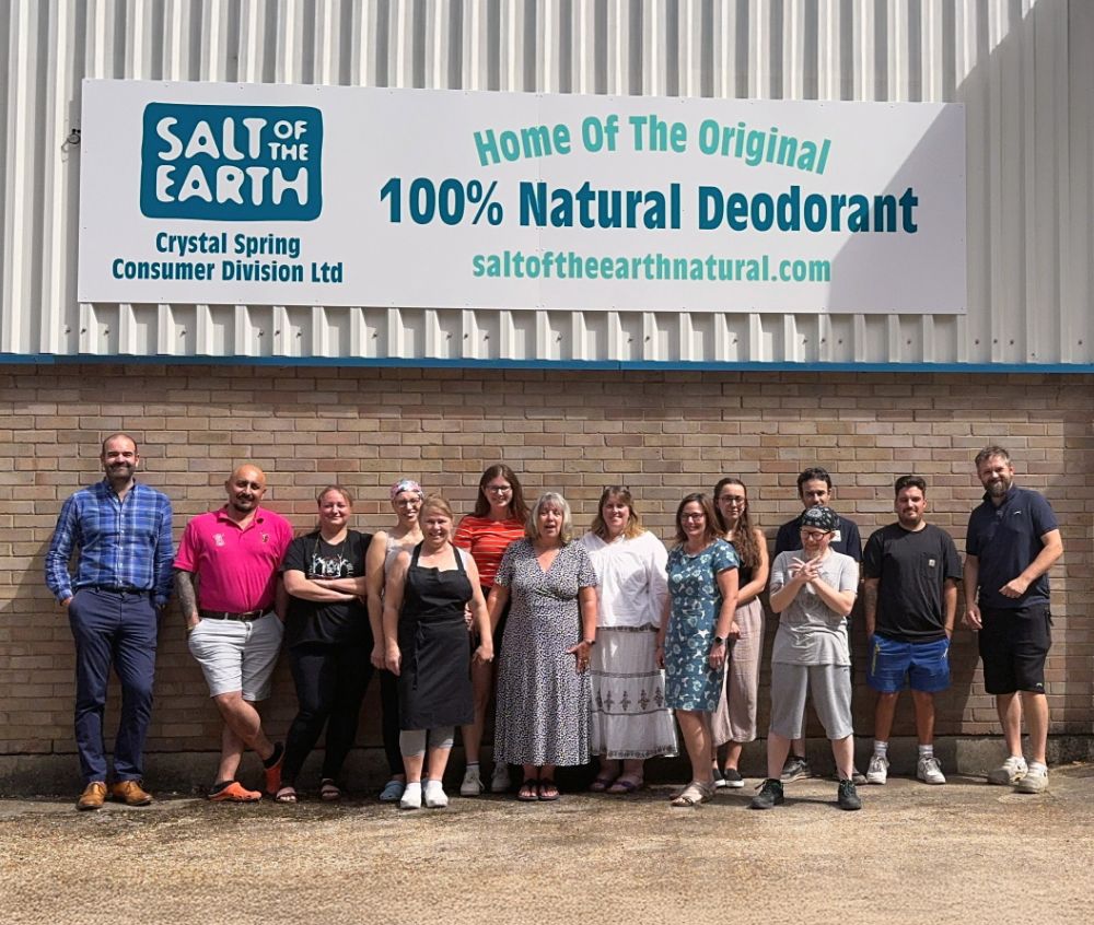 Salt of the Earth team standing outside headquarters under signage promoting 100% natural deodorant